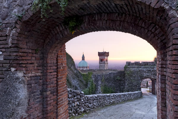 The gateway of the Rocca di Lonato frames the civic tower and the Basilica of Lonato del Garda. Brescia province, Lombardy, Italy, Europe.