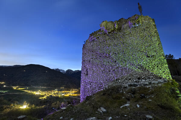 Spooky night at the medieval ruins of San Pietro castle. In the background the village of Torcegno. Valsugana, Trento province, Trentino Alto-Adige, Italy, Europe.