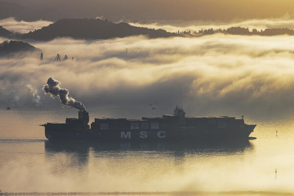 Container ship maneuvering in the port of La Spezia submerged by maritime fog, La Spezia province, Liguria district, Italy, Europe.

