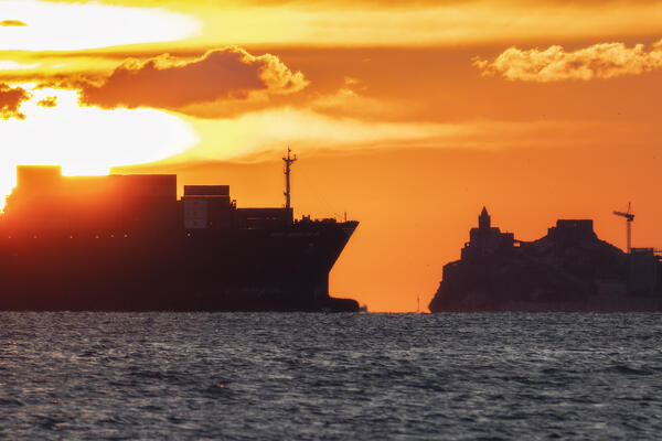 The sun sets on the Portovenere canal during the passage of a container ship, municipality of Portovenere, La Spezia province, Liguria, Italy, Europe
