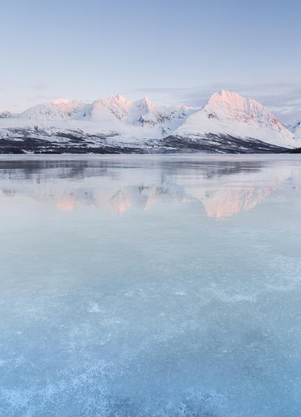 Norvegian Alps reflect themselves onto a frozen lake, Norway