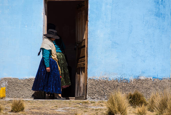 Young Ayamara women in the typical costume just outside her colored house. Aymaras are the native population of the Titicaca Lake area, in Bolivia, South America.