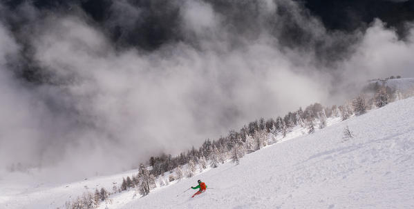 A freerider skiing over the clouds in a powder slope, Cima della Rosetta, Valgerola, Valtellina, Italy, Alps