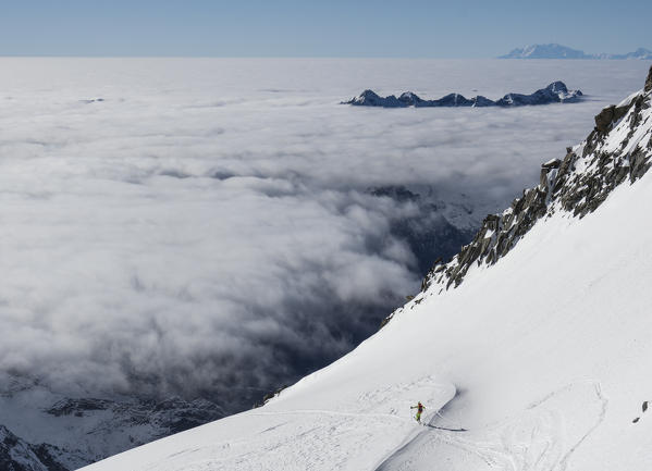 Skier over the clouds at Sella di Pioda, Valmasino, Valtellina, Lombardy, Italy, Alps