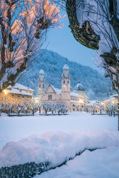 Europe, Italy, Veneto, Belluno province. The historic center of Agordo with the church and the snow-covered park of Broi