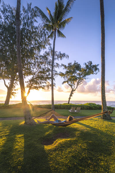 A girl relaxing herself on a hammock at sunrise in Kapaa beach park, Kauai island, Hawaii, USA