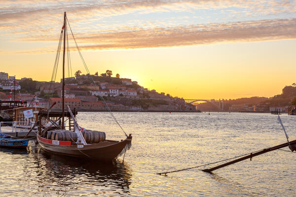 Sunset on Port wine boats moored on the south bank of Douro River, whit Arrábida Bridge on the background, Vila Nova de Gaia, Porto district, Norte Region, Portugal