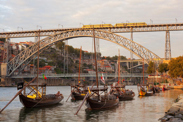Sunset on Port wine boats moored on the south bank of Douro River, whit Dom Luis I Bridge on the background, Vila Nova de Gaia, Porto district, Norte Region, Portugal