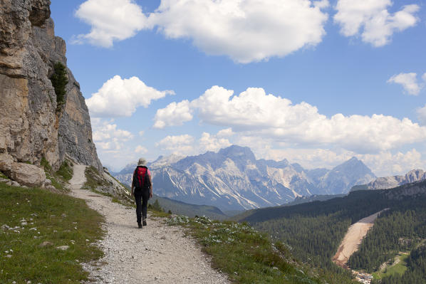 A hiker on the footpath above Falzarego Pass, with Sorapis and Antelao on the background, Dolomites. Cortina d'Ampezzo, Belluno province, Veneto, Italy.
