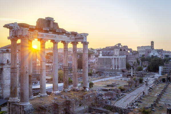 The Roman Forum at sunsrise, with Temple of Saturn in foreground and Colosseum in background, Rome, Lazio, Italy.