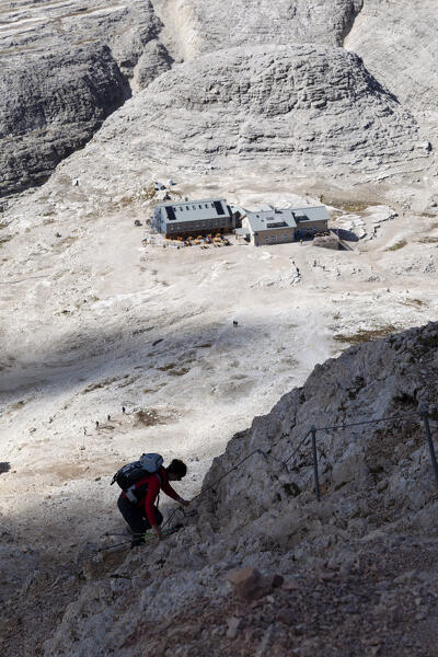 A hiker descends towards Boè refuge, Sella Group, Dolomites, Trentino - Alto Adige, Italy.