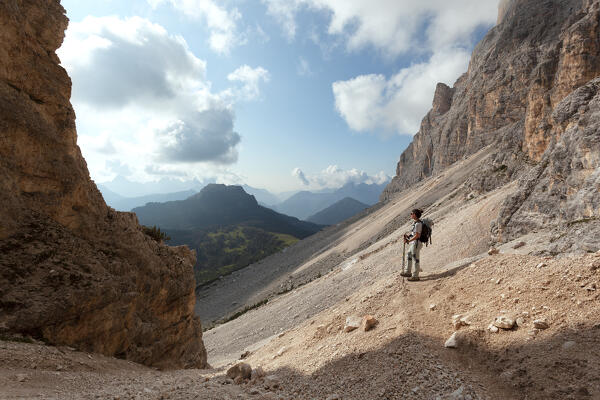 A hiker admires the landscape from Sentiero Flaibani (Flaibani trail), Pelmo group, Dolomites, Belluno province, Veneto, Italy.