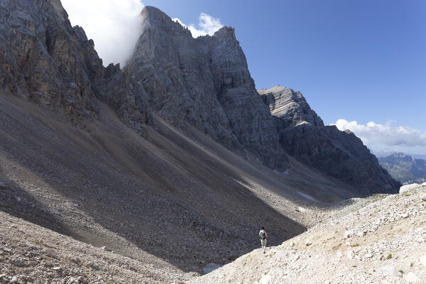 A hiker in front of the north face of Pelmo Mount, near Forcella Val d'Arcia, Dolomites, Borca di Cadore, Belluno Province, Veneto, Italy.