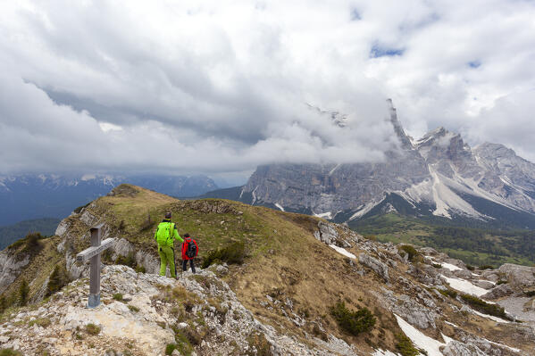 Two hiker descend from the summit of Penna Mount, with Pelmo Mount on the background, Dolomites, Zoppè di Cadore,  Belluno province, Veneto, Italy.