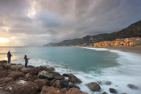 Fishermen on Varigotti beach during a cloudy sunset, Finale Ligure, Savona province, Liguria, Italy
