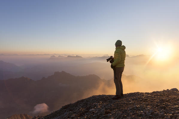 A photographer admires the sunrise at Punta Penia, Marmolada group, Dolomites, Canazei, Trento province, Trentino-Alto Adige, Italy