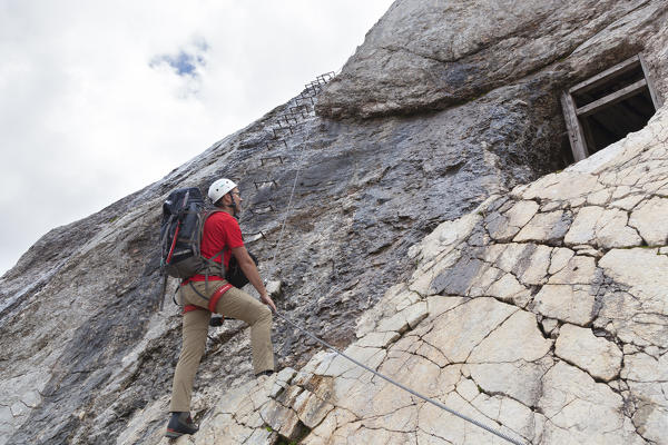 A hiker at Forcella Marmoalda, start of Via Ferrata of West Ridge, Marmolada group, Dolomites, Canazei, Trento province, Trentino-Alto Adige, Italy