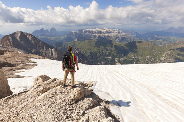 A mountaineer admires the Sella group from the end of Via Ferrata of West Ridge, Marmolada group, Dolomites, Canazei, Trento province, Trentino-Alto Adige, Italy