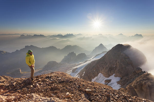 A hiker admires the panorama at Punta Penia, Marmolada group, Dolomites, Canazei, Trento province, Trentino-Alto Adige, Italy