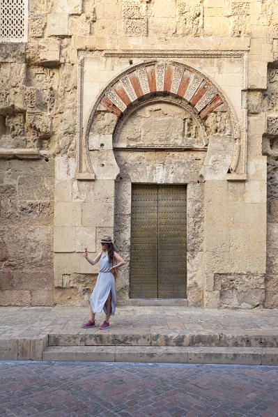 A tourist takes a selfie in front of Puerta de San Esteban, Mosque–Cathedral of Córdoba, Córdoba municipality, province of Córdoba, Andalusia, Spain