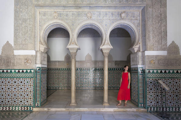 A woman in a typical arabic horseshoe arch in Palacio de Pedro I (Palace of Peter I), Royal Alcazars of Seville, Seville, province of Seville, Andalusia, Spain (MR)