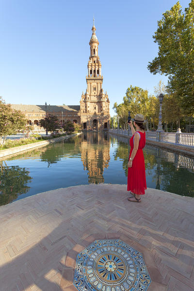A tourist photographs te south tower of Plaza de España, Maria Luisa Park, Seville, province of Seville, Andalusia, Spain