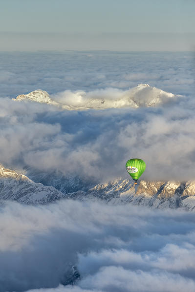 Seefeld, Tyrol, Austria, Europe. Crossing the alps in a hot air balloon. Under the fog the Inn Valley, in the background the highest mountain in Germany, the Zugspitze at sunrise
