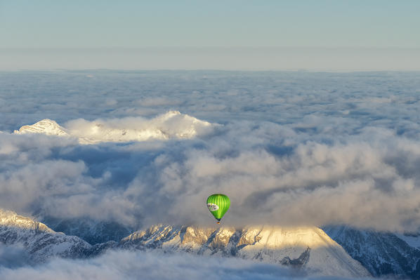 Seefeld, Tyrol, Austria, Europe. Crossing the alps in a hot air balloon. Under the fog the Inn Valley, in the background the highest mountain in Germany, the Zugspitze at sunrise