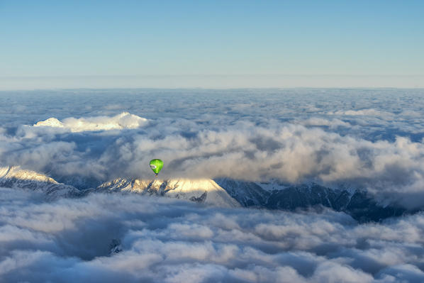 Seefeld, Tyrol, Austria, Europe. Crossing the alps in a hot air balloon. Under the fog the Inn Valley, in the background the highest mountain in Germany, the Zugspitze at sunrise
