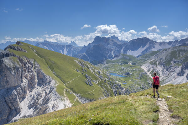 Valdaora / Olang, Bolzano province, South Tyrol, Italy, Europe. A girl hikes from the summit of Piz da Peres to the Lake Foiedora. In the background the Tre Cime di Lavaredo (MR)