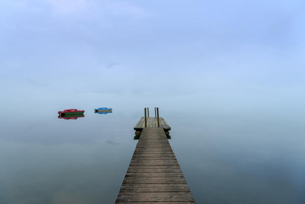 Kochel am See, Bad Tölz-Wolfratshausen district, Upper Bavaria, Germany, Europe. Jetty with two pedal boats in the Kochel Lake at dawn
