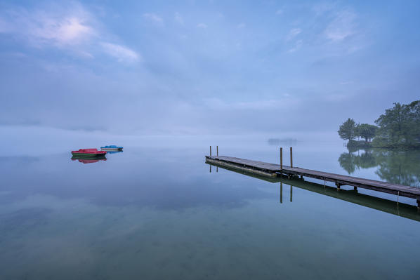 Kochel am See, Bad Tölz-Wolfratshausen district, Upper Bavaria, Germany, Europe. Jetty with two pedal boats in the Kochel Lake at dawn