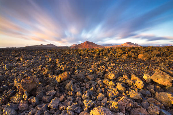 Volcanic rocks with volcanos and moving clouds in the background - Lanzarote, Canary Islands
