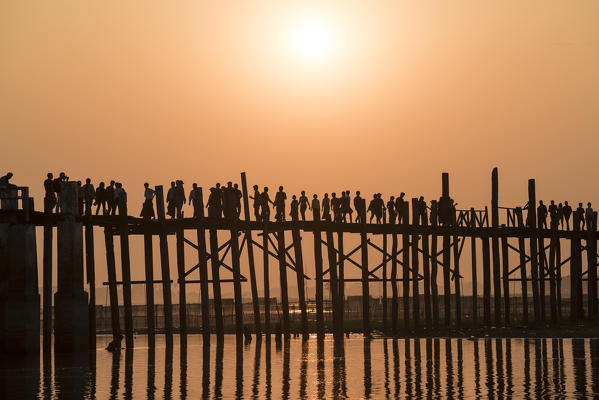 Amarapura, Mandalay region, Myanmar. Silhouetted people walking on the U Bein bridge at sunset.