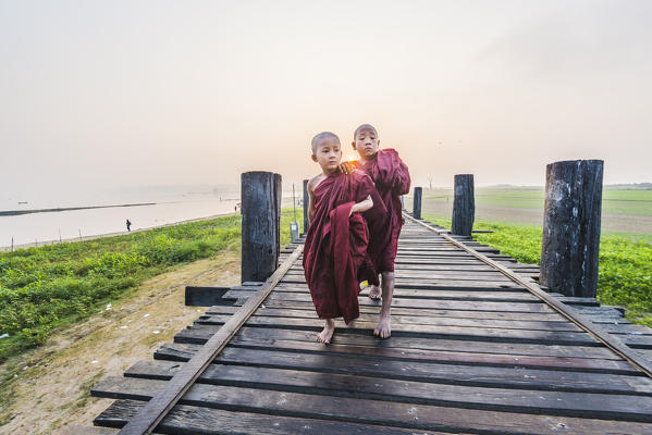 Amarapura, Mandalay region, Myanmar. Monks walking on the U Bein bridge at sunrise.