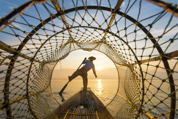 Inle lake, Nyaungshwe township, Taunggyi district, Myanmar (Burma). Local fisherman seen through the typical fishing net at sunrise.