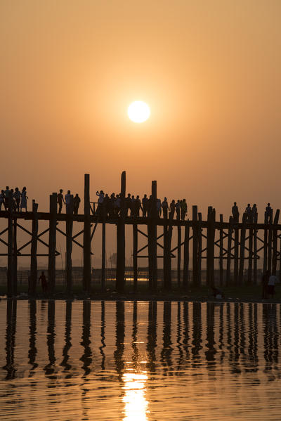 Amarapura, Mandalay region, Myanmar. Silhouetted people walking on the U Bein bridge at sunset.