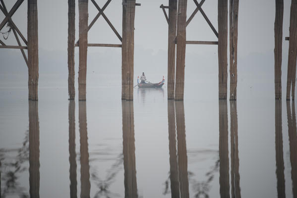Amarapura, Mandalay region, Myanmar. Man rows his boat below the piles of the U Bein bridge