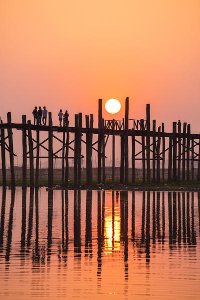 Amarapura, Mandalay region, Myanmar. Silhouetted people walking on the U Bein bridge at sunset.