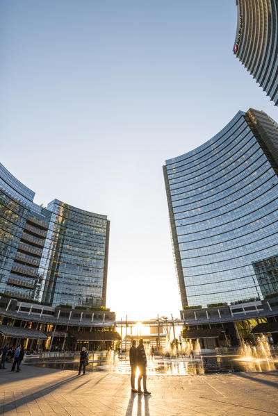 Milan, Lombardy, Italy. People in Gae Aulenti square in the Porta Nuova business district at sunset.