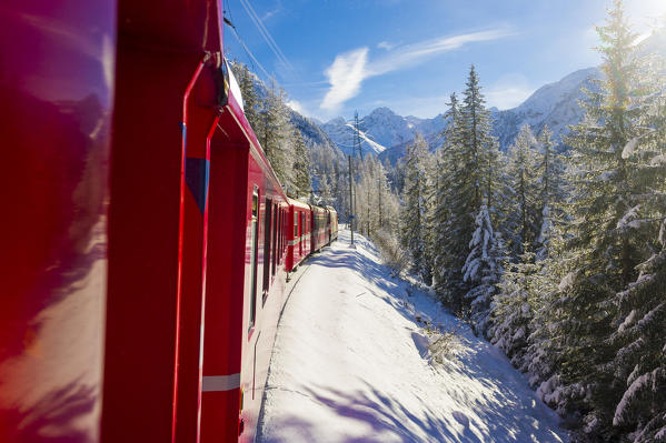 Iconic swiss red Bernina Express train in winter landscape and pristine snow. Swizerland, Europe.