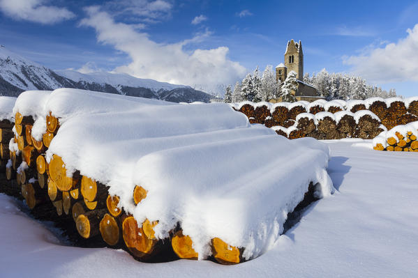 Trunks and old church in Celerina with pristine snow. Engadine, Switzerland, Europe