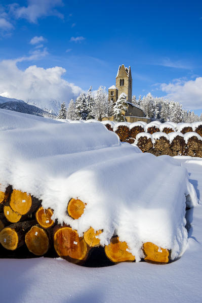 Trunks and old church in Celerina with pristine snow. Engadine, Switzerland, Europe