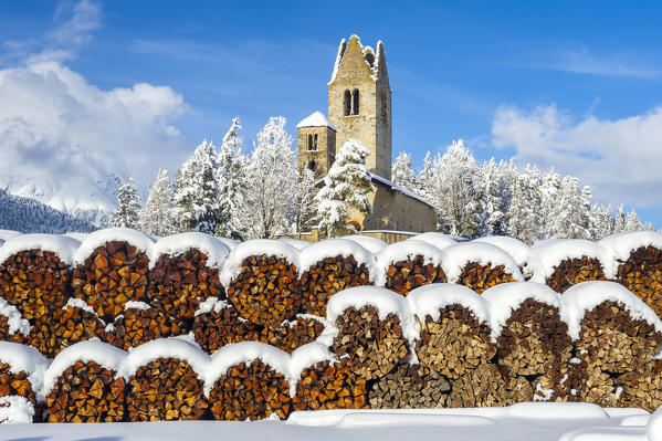 Trunks and old church in Celerina with pristine snow. Engadine, Switzerland, Europe