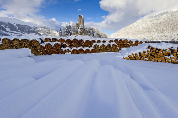 Trunks and old church in Celerina with pristine snow. Engadine, Switzerland, Europe