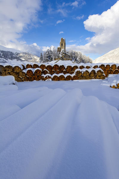 Trunks and old church in Celerina with pristine snow. Engadine, Switzerland, Europe
