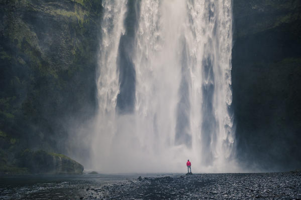 Southern Iceland. Man stands below the Skogafoss waterfall.