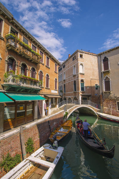 Venice, Veneto, Italy. Gondola sailing through a street canal.
