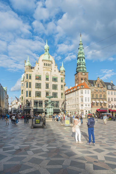 Copenhagen, Hovedstaden, Denmark. Tourists and bars in Amager square (Amagertorv) with St. Nicholas church in the background.