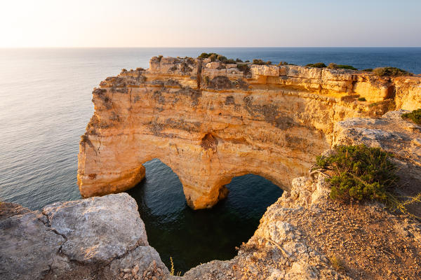 Heart shaped rock near Praia da Marinha, Algarve, Portugal. View at sunrise
